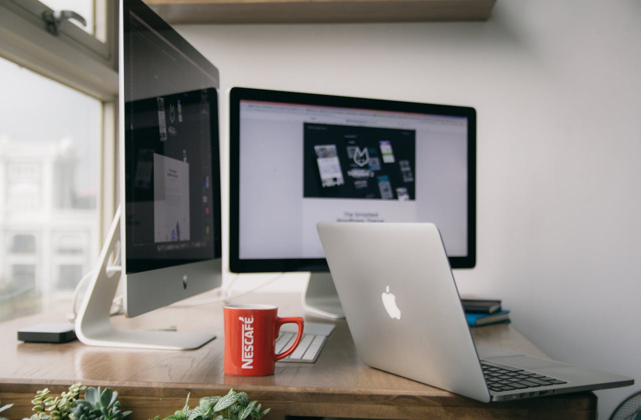 A bright modern office setup with computers and a mug on a desk.